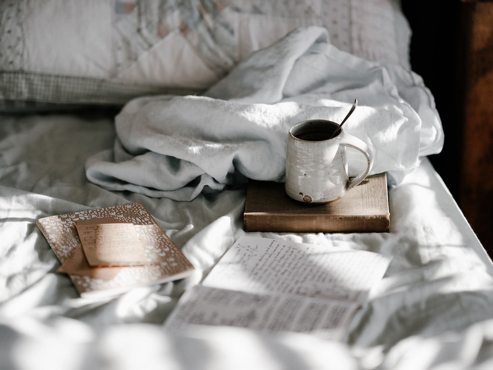 caneca branca e livros na cama