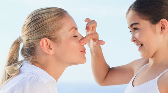 menina a colocar protetor solar no rosto da mãe