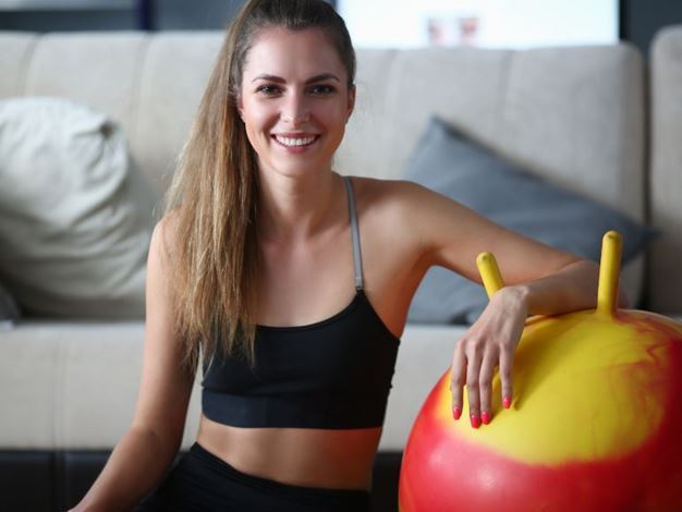 Mulher apoiada em bola de pilates